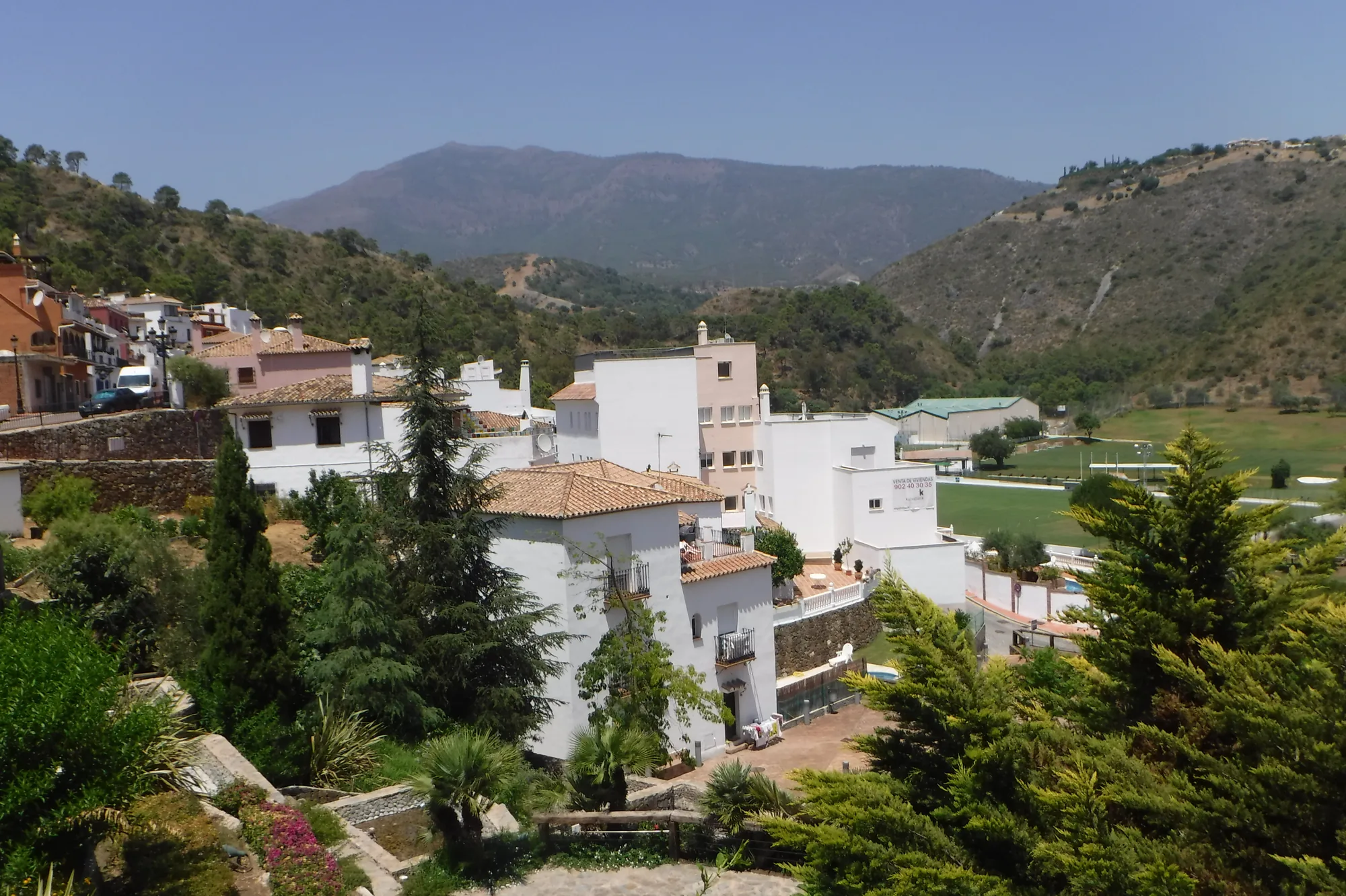 Whitewashed houses on a hillside in Benahavís, with the surrounding mountains and valley behind them