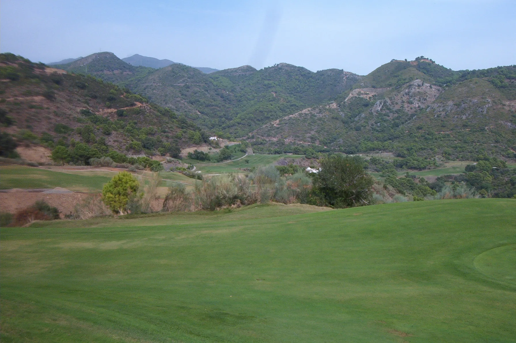 Fairway and green surrounded by wooded mountains on a golf course in Benahavís, Málaga
