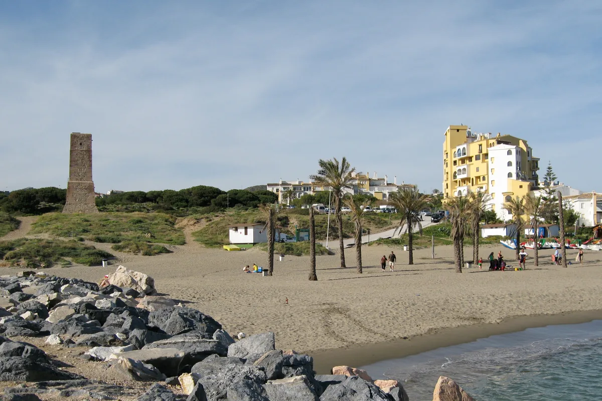 Cabopino beach with the Torre Ladrones watchtower on the dunes and apartment buildings behind the shore