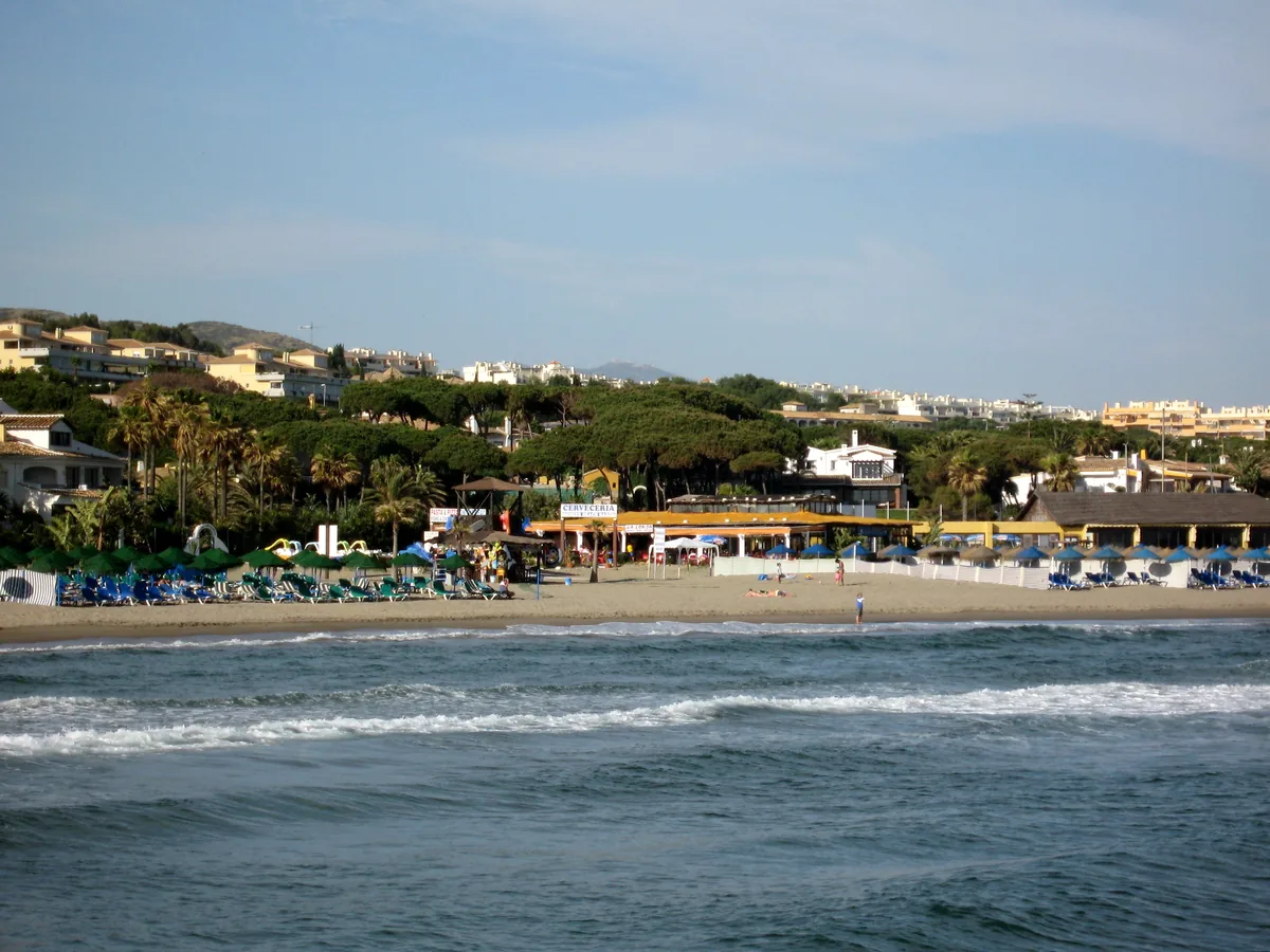 Houses and low apartment buildings on the slope above the beach at Cabopino, Marbella