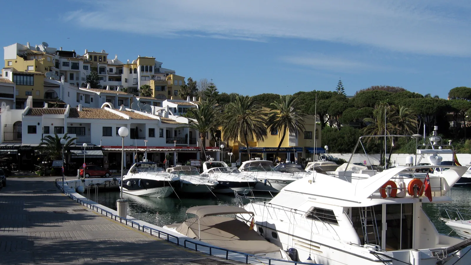 Boats moored at Cabopino marina in eastern Marbella, with low whitewashed buildings behind the quay