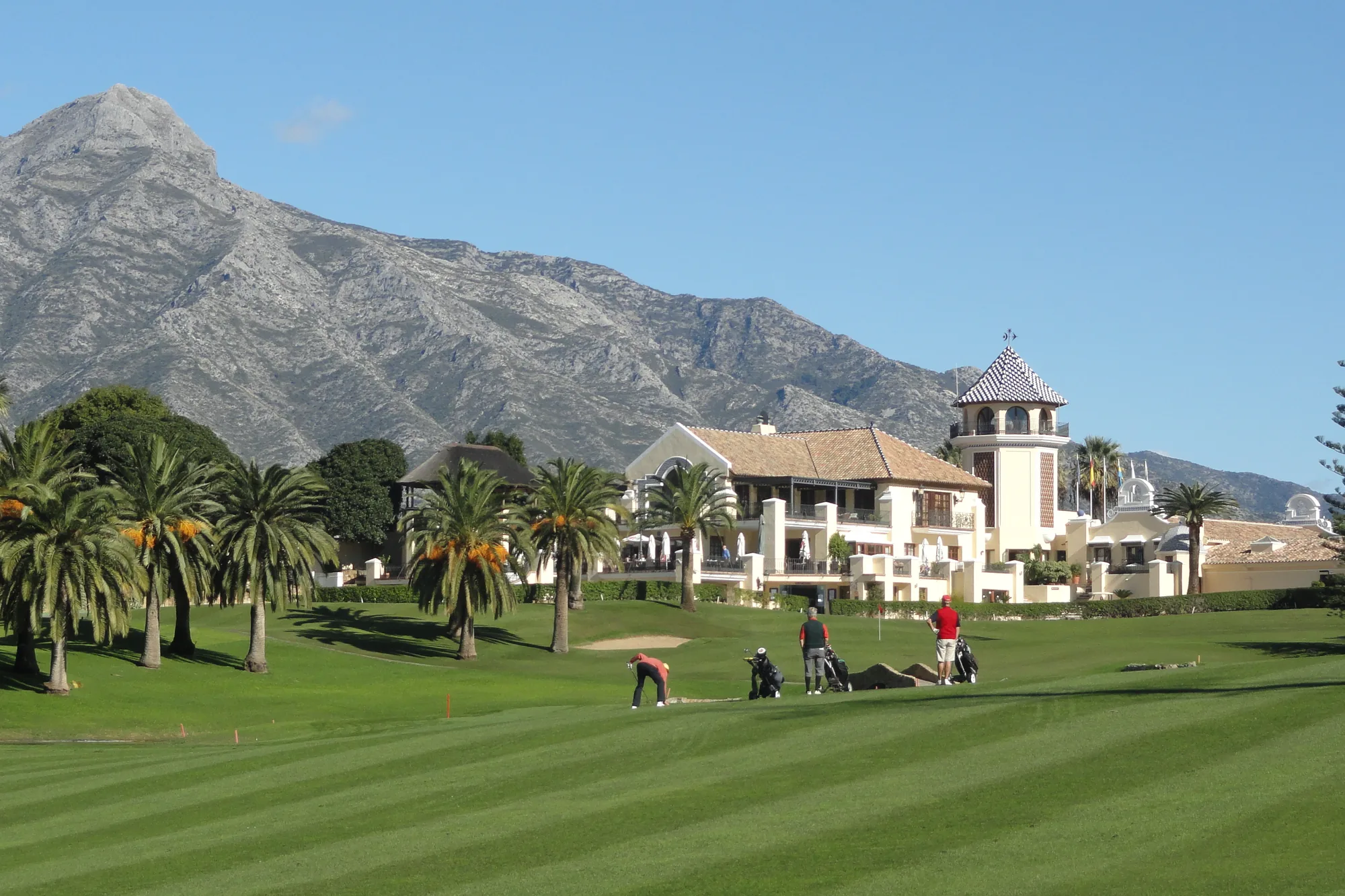 Fairway, clubhouse and palm trees at Los Naranjos Golf Club in Nueva Andalucía, Marbella, with La Concha mountain behind
