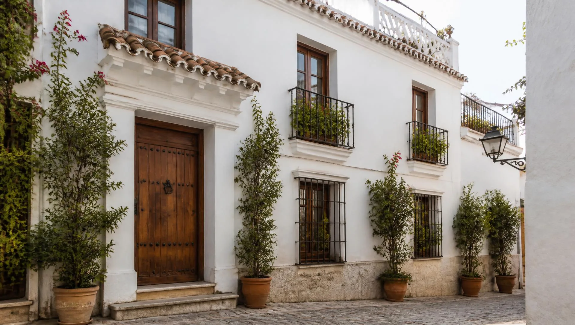 Traditional multi-level whitewashed house with wooden door and iron balconies on a cobbled street in Marbella Old Town