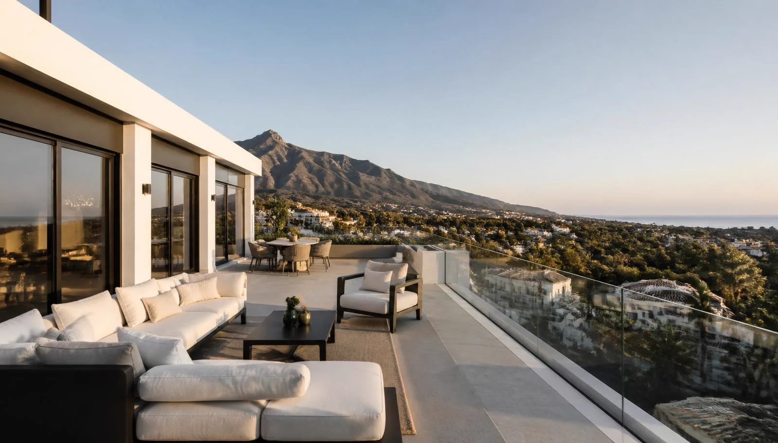 Terrace of a top-floor apartment in Marbella with outdoor seating and a view towards the mountains and coast