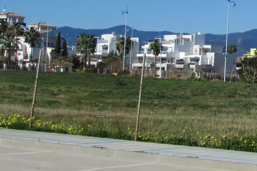 Modern white residential blocks beside an undeveloped plot in San Pedro de Alcántara, Marbella
