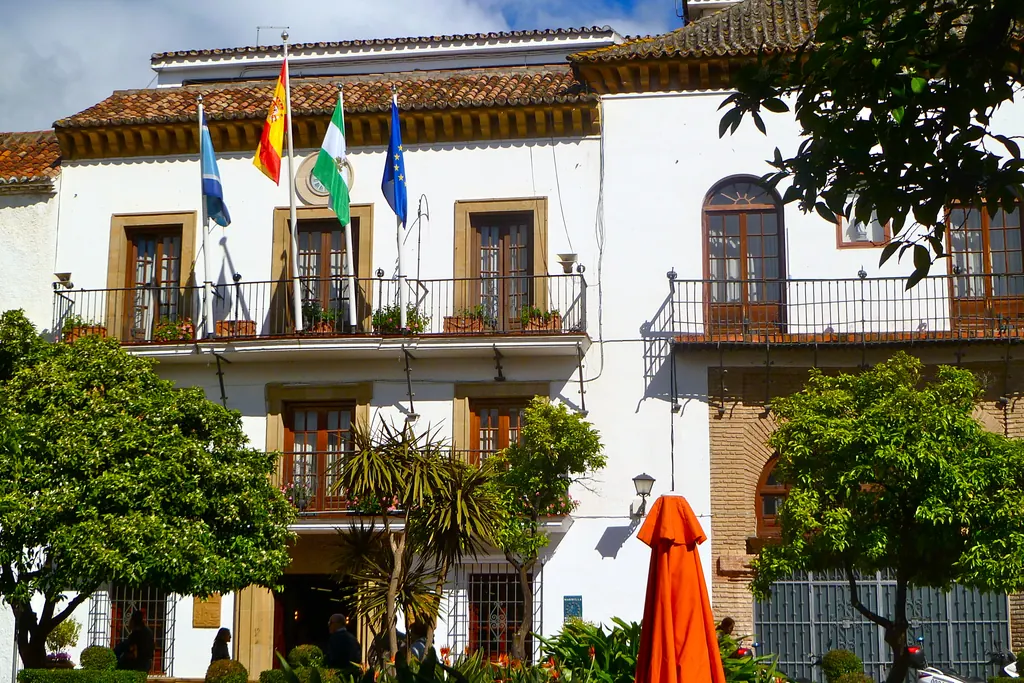 Whitewashed town hall building in Marbella with Spanish, Andalusian and European flags on the balcony
