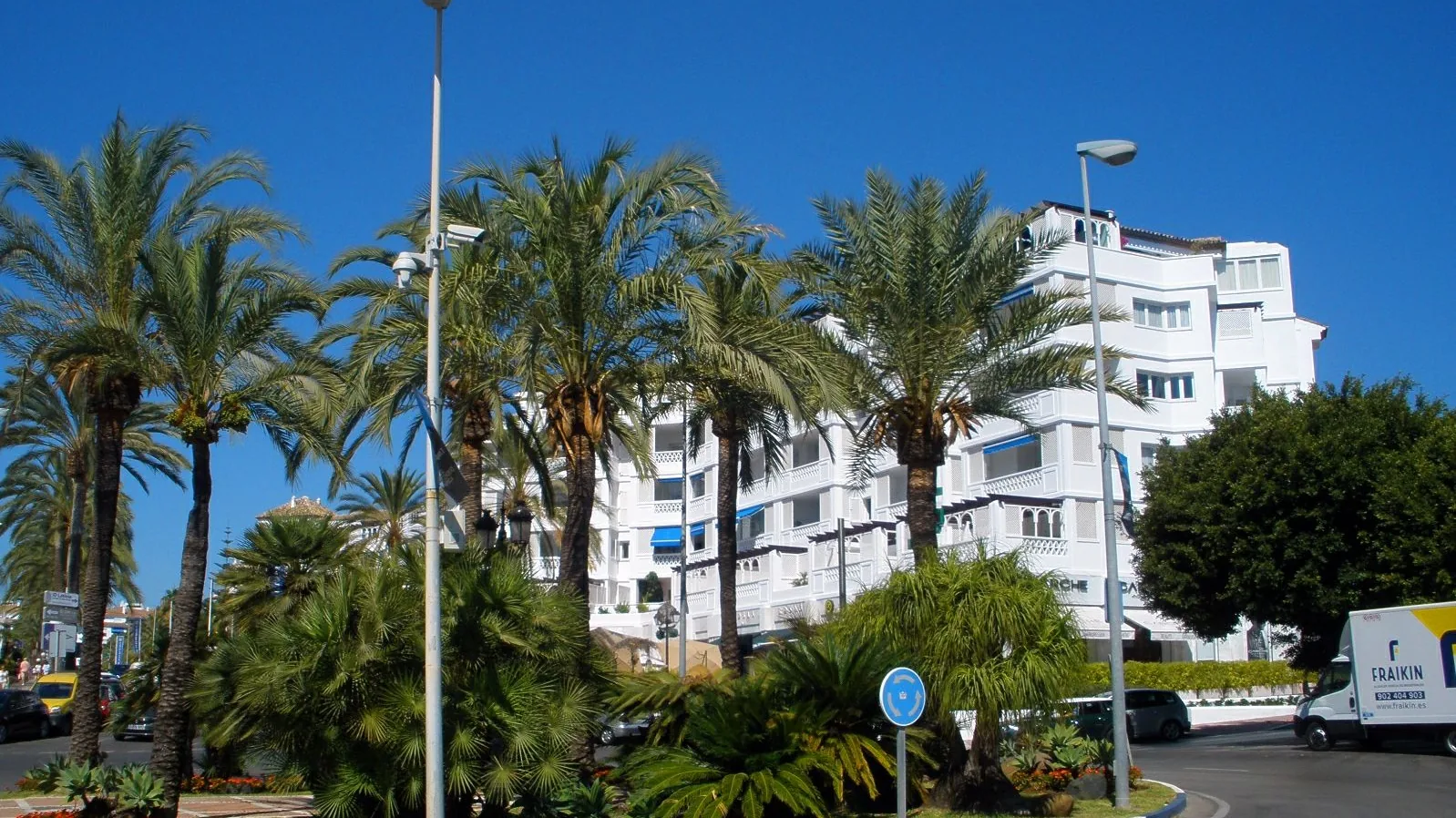 Low-rise white apartment buildings surrounded by palm trees in Nueva Andalucía, Marbella