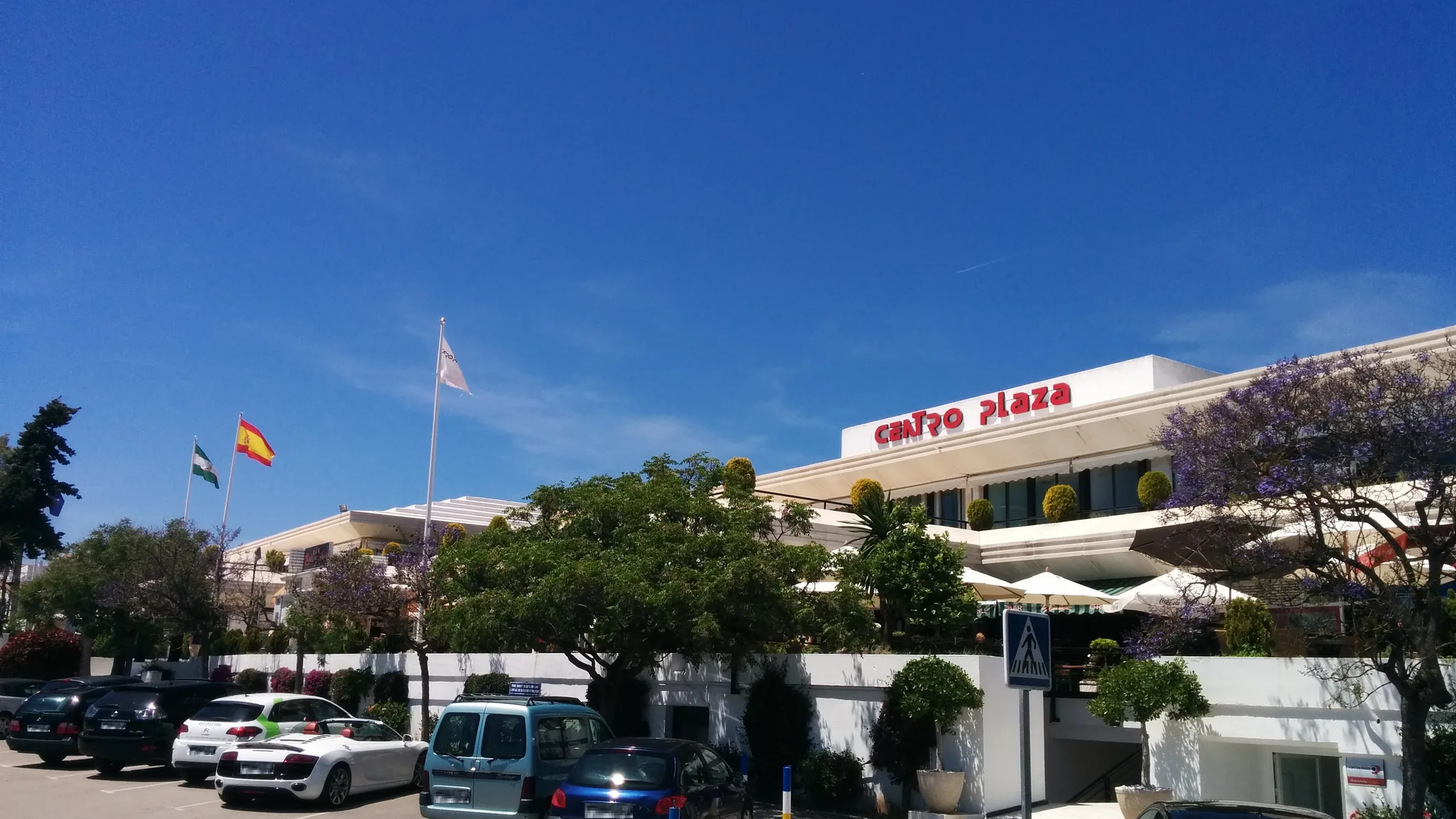 Centro Plaza commercial centre with palm trees and parked cars in Nueva Andalucía, Marbella