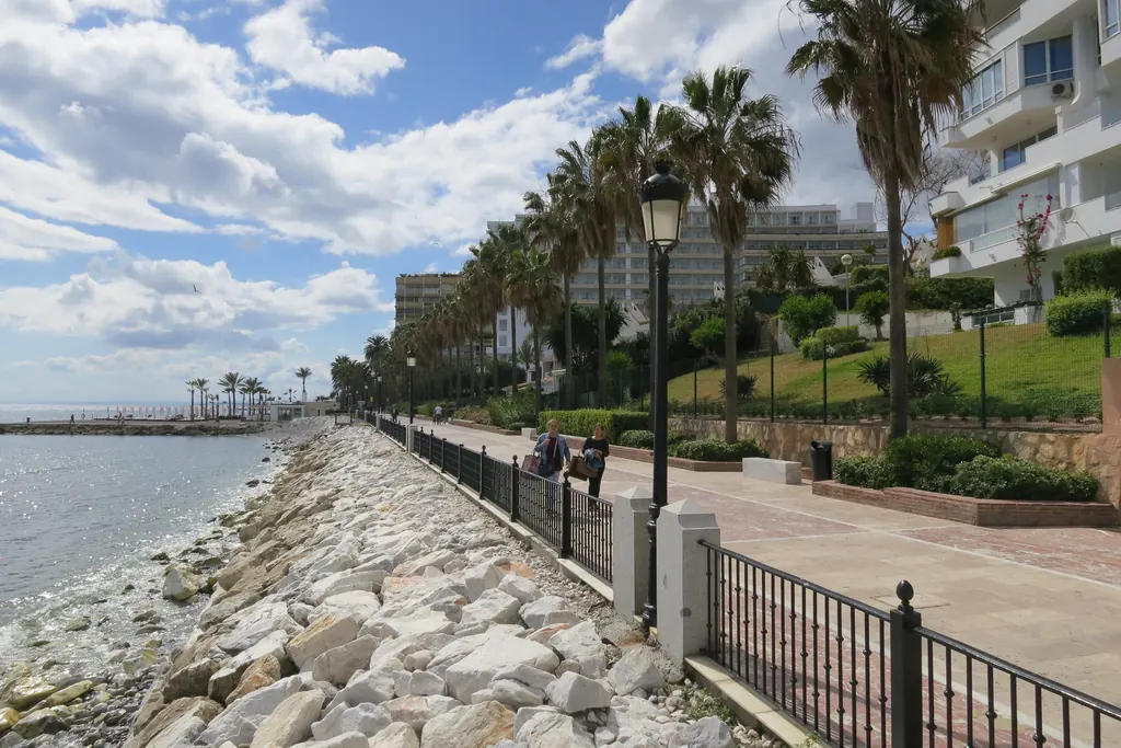 Coastal walkway in Marbella running past low apartment blocks and gardens