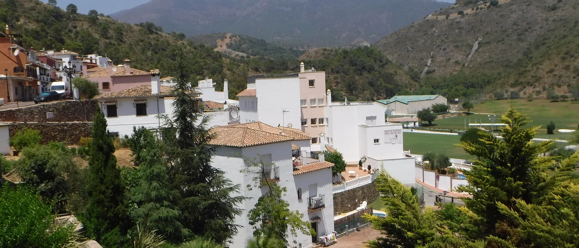 View across the Benahavís valley towards wooded ridges, with low white houses on the slopes
